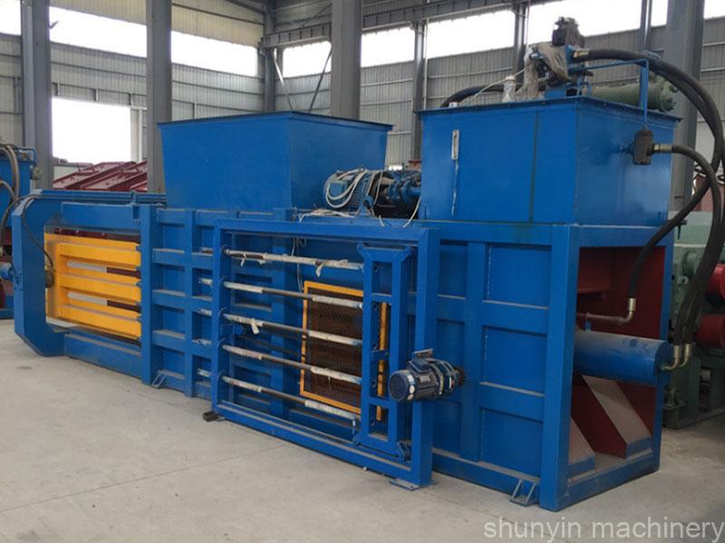 Horizontal baling machine for recycling cardboard, plastics, and other materials.