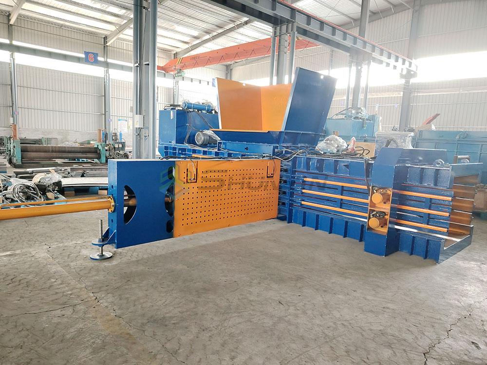 Worker operating horizontal baler machine with recycled materials